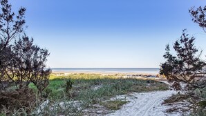 A sandy path leading to a beach with sparse vegetation and a clear sky. - Stanton Apartment C - Historic retreat 1 block to beach (Saint Simons Island)