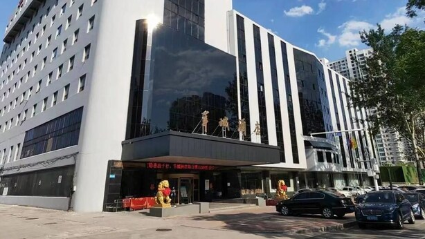 A modern hotel with a prominent entrance, large windows, and a parking area. - Yangcheng Hotel (Qinhuangdao)