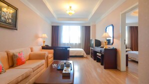 A hotel room with a sofa, a bed, a desk with a television, and a dining table with a tray of items. - Yangcheng Hotel (Qinhuangdao)