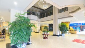 A spacious lobby with a large potted plant, a chandelier, and a red carpet. - Yangcheng Hotel (Qinhuangdao)