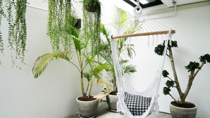 A room with a hanging chair, potted plants, and a hammock. - The Companion - Hostel (Bangkok)
