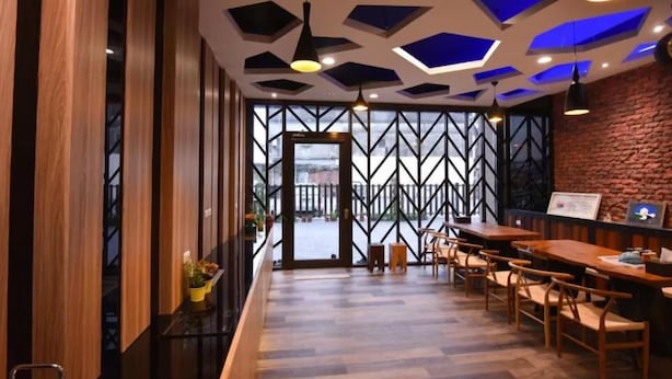Un intérieur moderne avec un lambris en bois, un mur en briques et un plafond au motif géométrique.