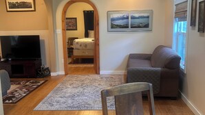 Un salon avec un plancher en bois, un canapé, un téléviseur et une table à manger.