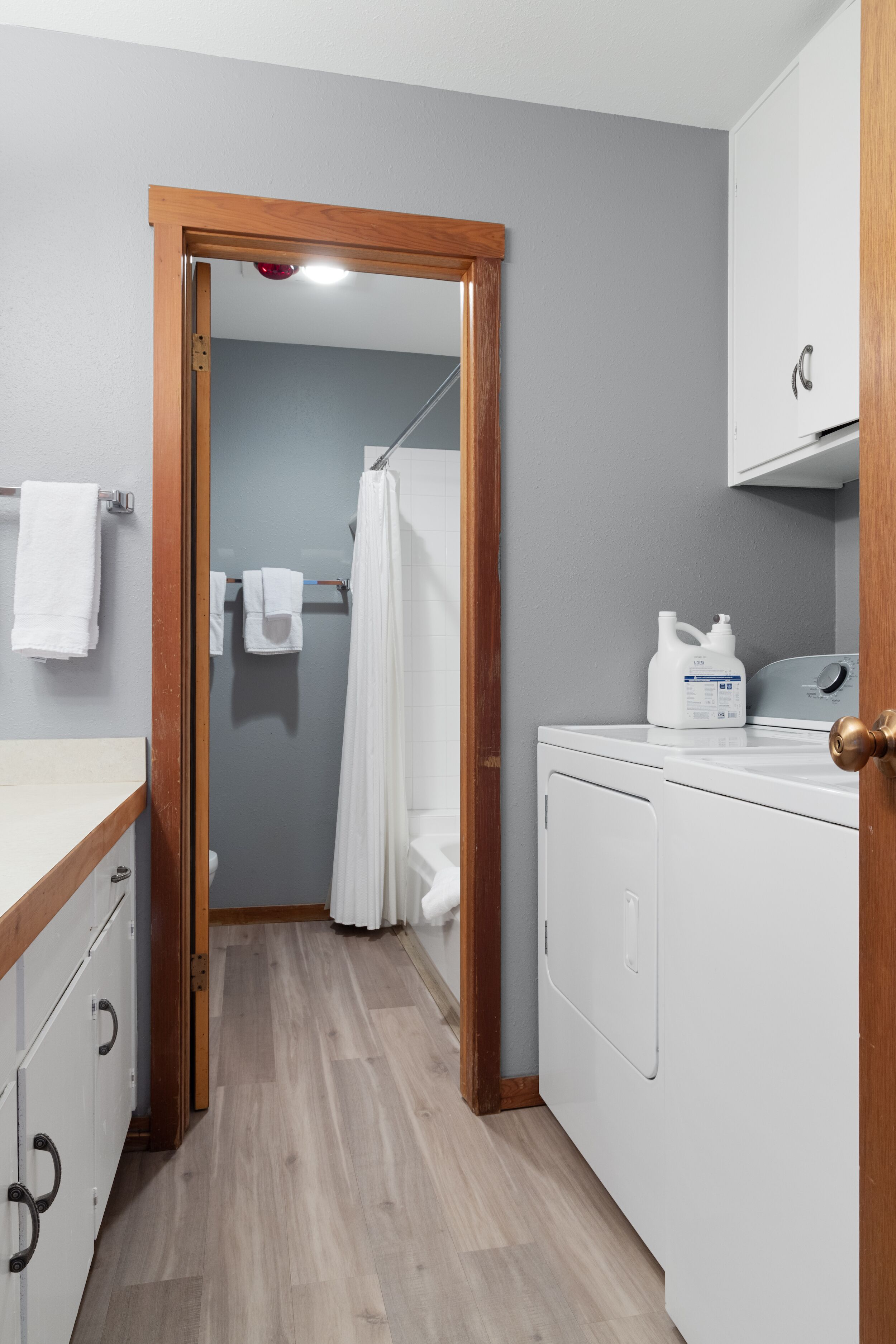 A laundry area with a washing machine, a drying rack, and a wooden door frame.