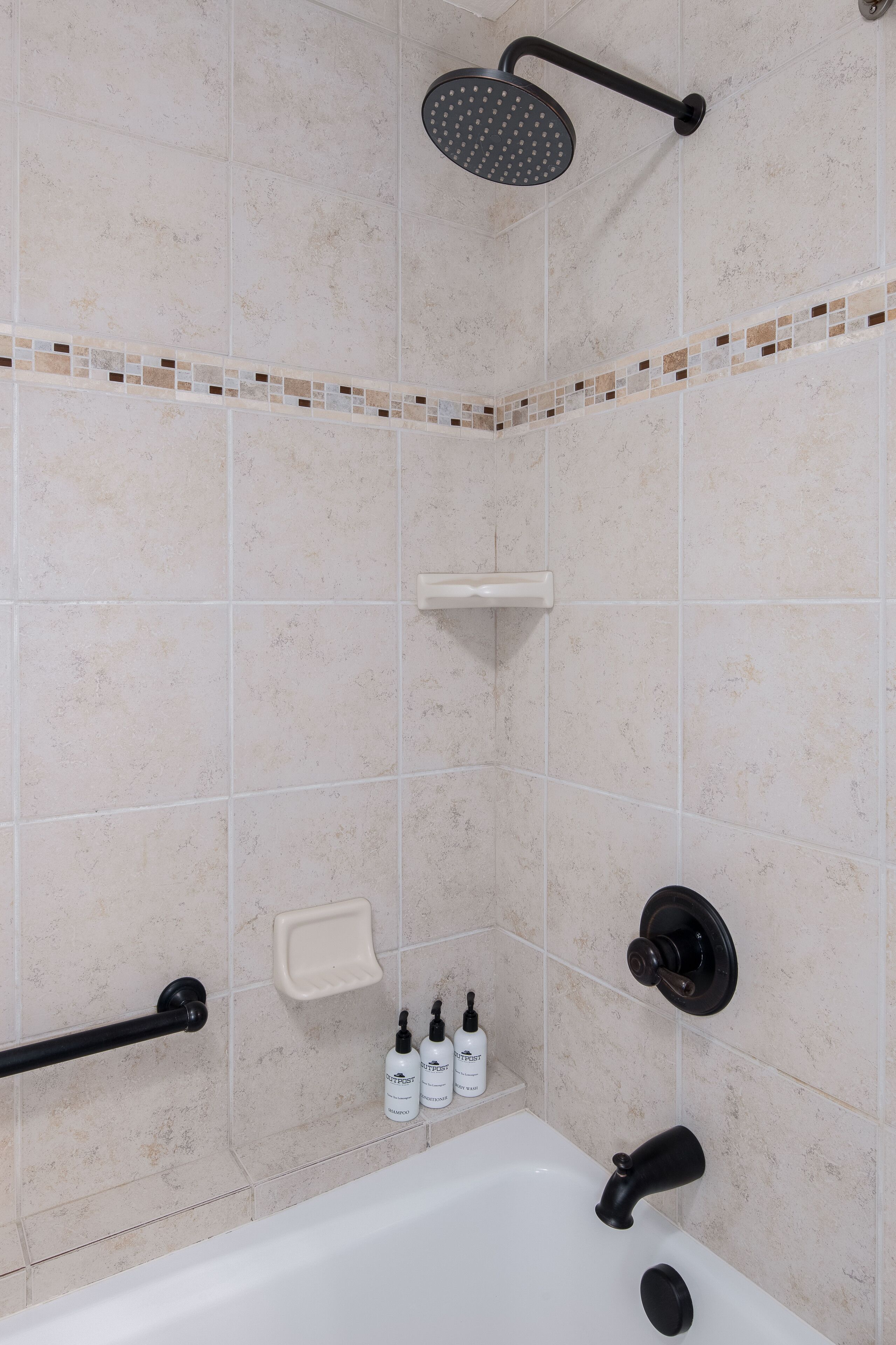 Un bagno con una vasca, una doccetta e due flaconi di bagnoschiuma OutPost.