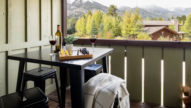 A balcony with a table set for wine tasting, overlooking a mountainous landscape. - Outpost: Geranium 2622 (Wilson)