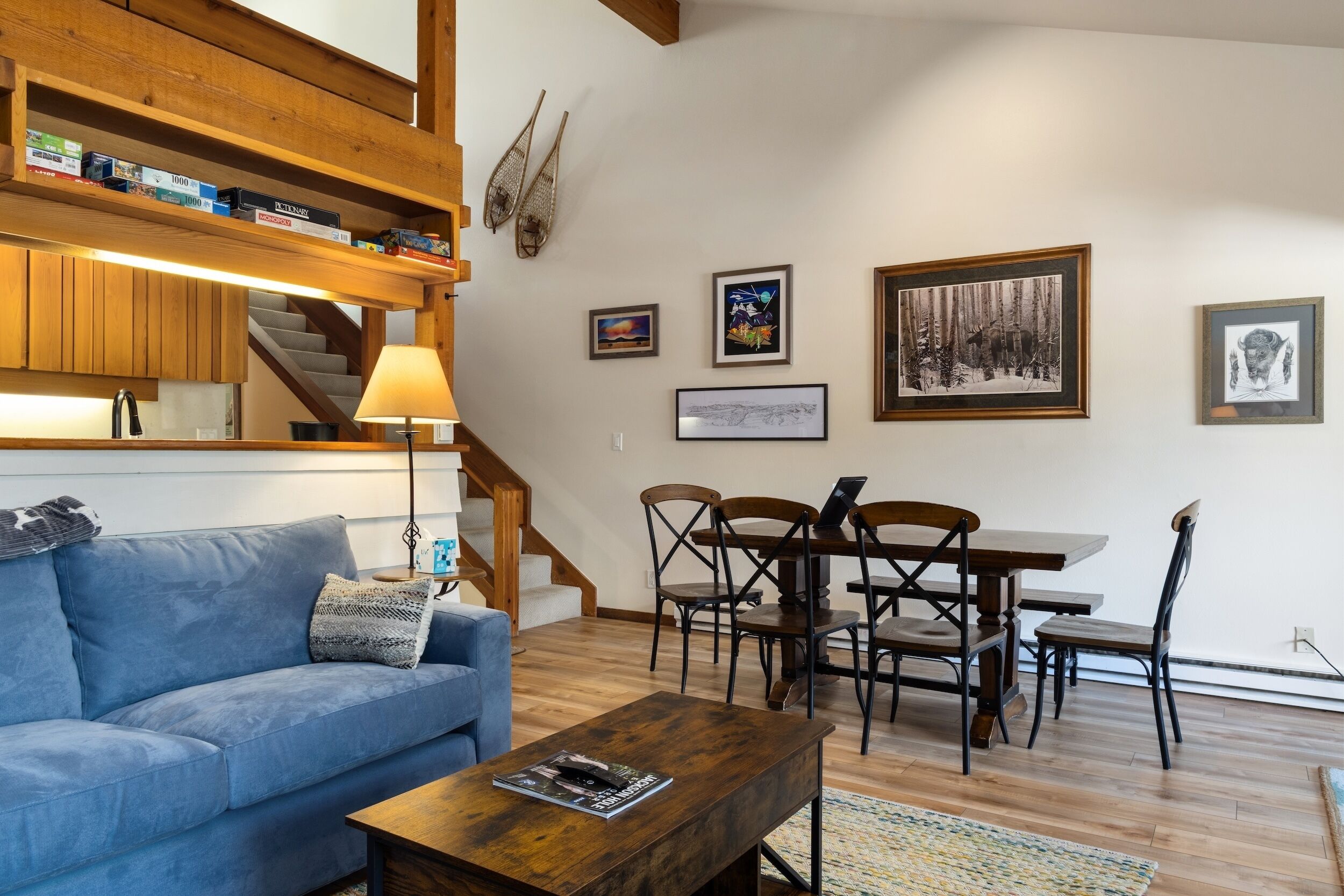 A living room with a blue sofa, wooden coffee table, and a dining area with a wooden table and chairs.