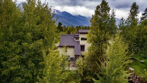 A multi-story building surrounded by dense green trees, with a mountain in the background. - Outpost: Geranium 2622 (Wilson)