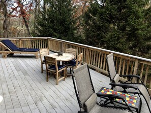 A wooden deck with lounge chairs, a table, and a mosaic-tiled chair.