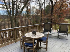 A wooden deck with a round table and chairs, surrounded by a wooden railing.