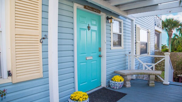 A turquoise door with a mailbox, a small porch with a white railing, and a planter with yellow flowers. - MARINA SUNSETS -- SAINT AUGUSTINE DOWNTOWN HISTORIC DISTRICT (St Augustine)
