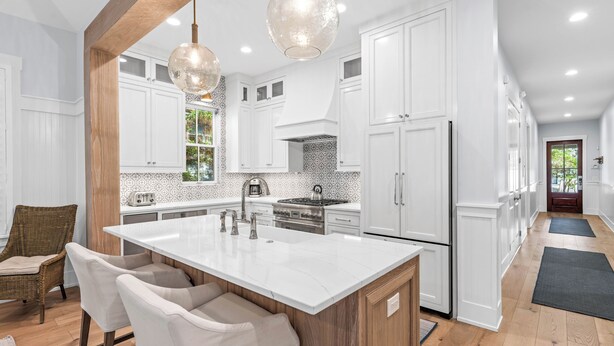 Una cocina moderna con armarios blancos, una isla grande e iluminación colgante.