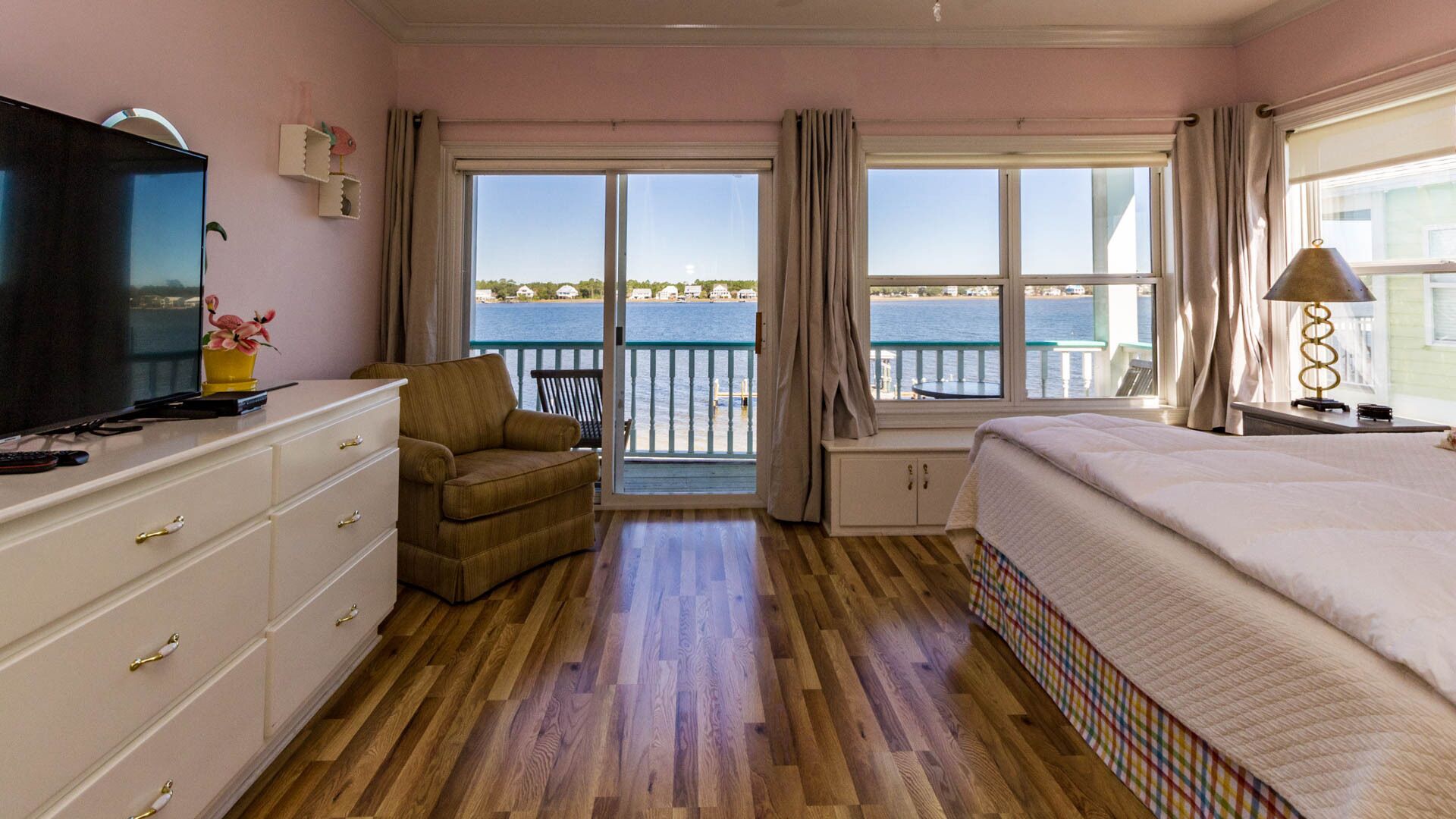Een hotelkamer met een groot bed, een televisie, een bank en een balkon met uitzicht op zee.