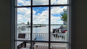 Une vue depuis une fenêtre donnant sur un quai où sont amarrés des bateaux, avec un ciel dégagé.