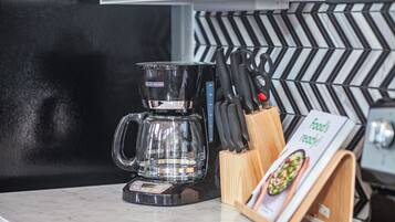 A coffee maker on a kitchen counter with a knife block and a menu stand.