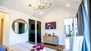 A bedroom with a bed, a dresser, a TV, and a large window.