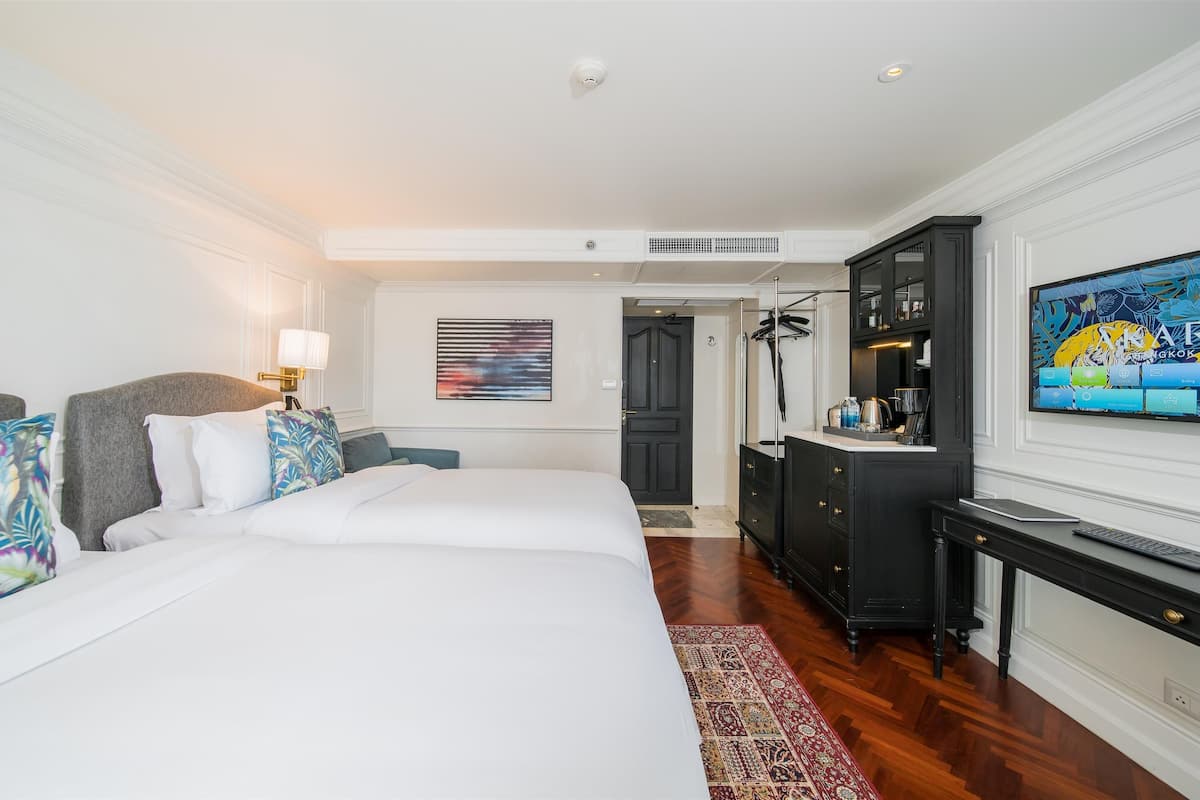 A hotel room with a large bed, a desk, a television, and a wardrobe.