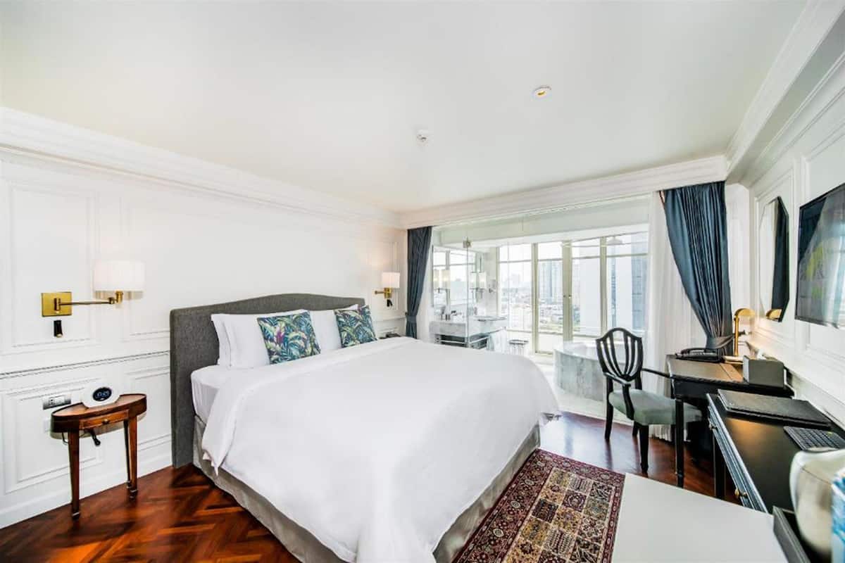 A hotel room with a large bed, a desk, and a chair.