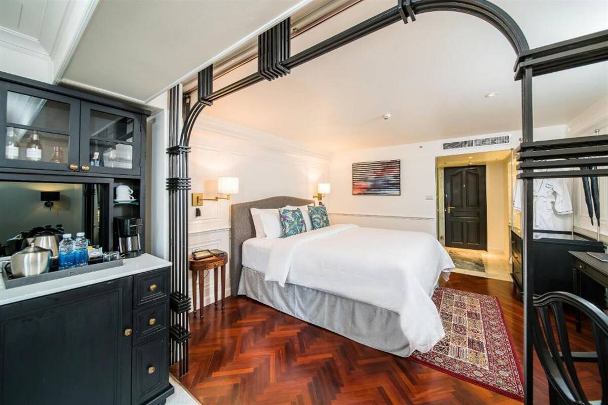 A bedroom with a large bed, a nightstand, a dresser, and a window.