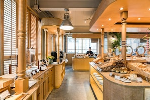 A restaurant with wooden decor, a buffet counter, and a chef preparing food. - Akara Hotel Bangkok (Bangkok)