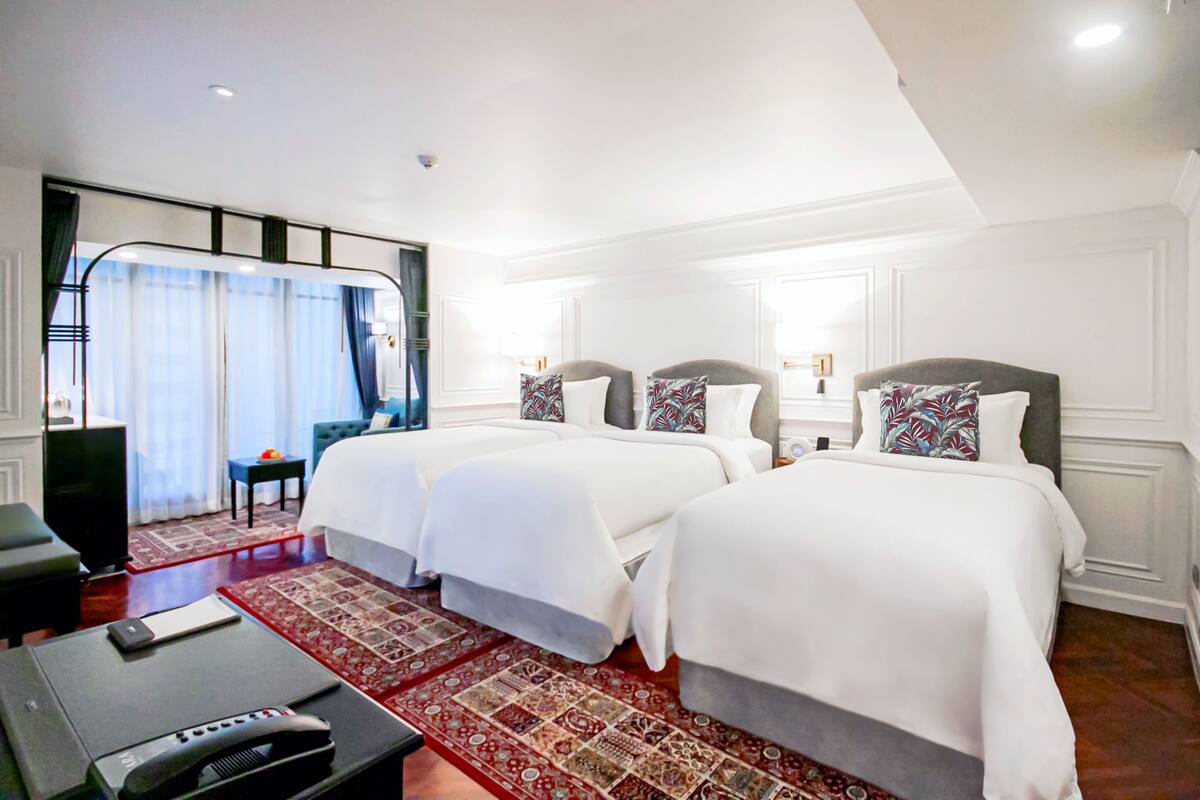 A hotel room with two beds, a television, and a red patterned rug.