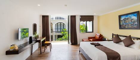 A modern hotel room with a large bed, a desk, and a view of a building through the window.