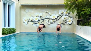 Piscina com um mural de flores e pássaros na parede.