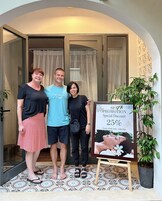 Three people standing in front of a spa promotion poster.