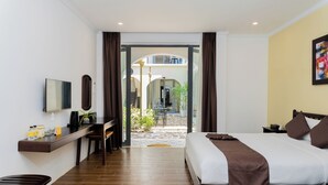 Quarto de hotel com cama, escrivaninha, televisão e vista para a área externa.