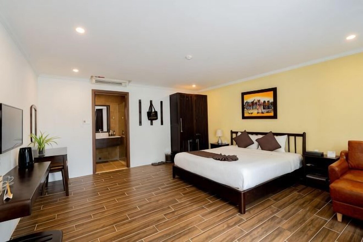 A hotel room with a bed, a desk, a chair, a TV, and a bathroom.