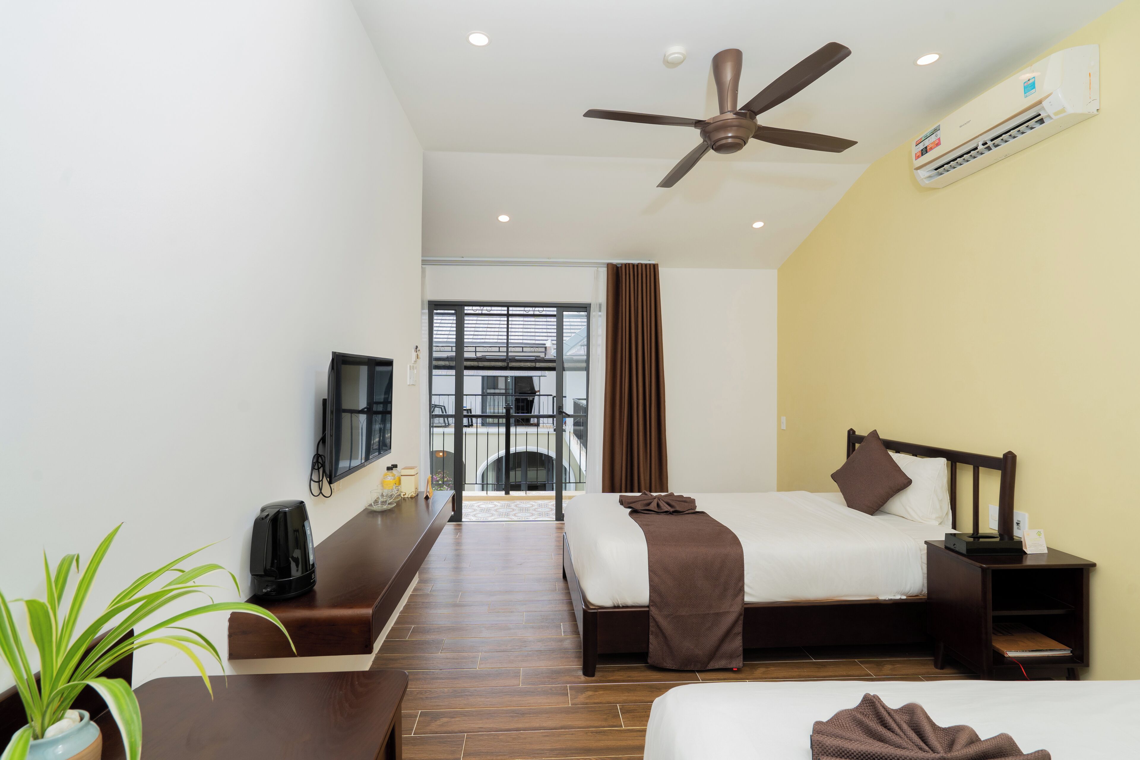 Une chambre d’hôtel équipée d’un lit, d’un bureau, d’un ventilateur de plafond et d’un appareil de climatisation.