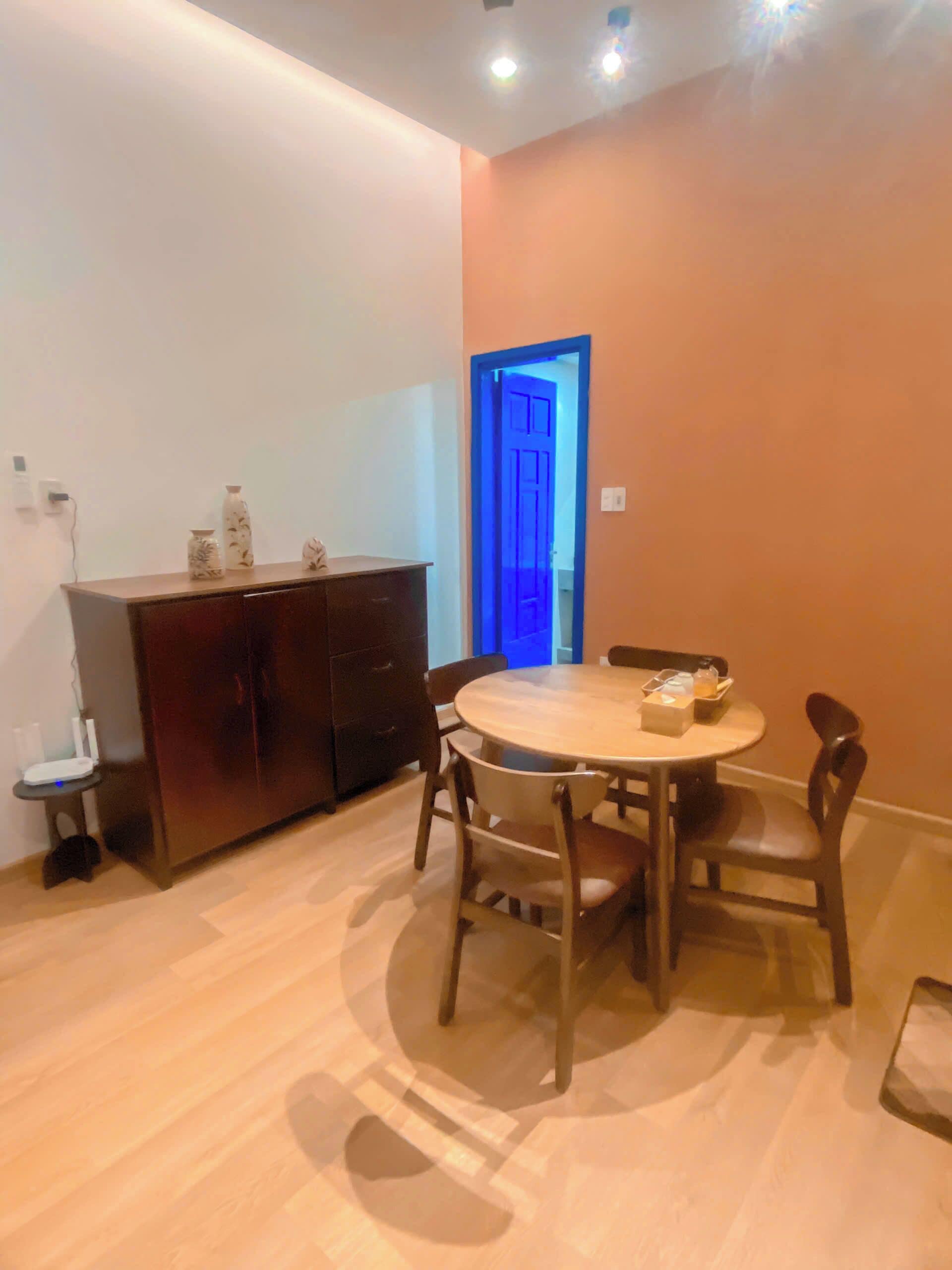 A dining area with a round table and chairs, a cabinet, and a blue-lit door.
