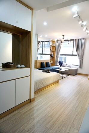 A modern bedroom with a bed, a sofa, a desk, and a wardrobe. - Studio Apartment near Airport (Ho Chi Minh City)