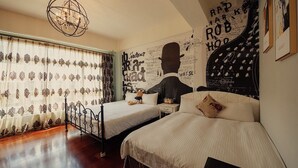 A bedroom with two beds, a chandelier, and a wall with abstract designs and text. - Hualien 5FM Homestay-Jianlin (Hualien City)