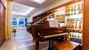 A grand piano in a well-lit room with a skylight, a display of trophies, and a wooden floor. - Hualien 5FM Homestay-Jianlin (Hualien City)