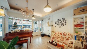A cozy living room with a piano, a floral sofa, and a coffee table. - Hualien 5FM Homestay-Jianlin (Hualien City)