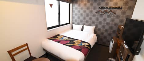 Une chambre d’hôtel avec un lit, une chaise, une télévision et une fenêtre.