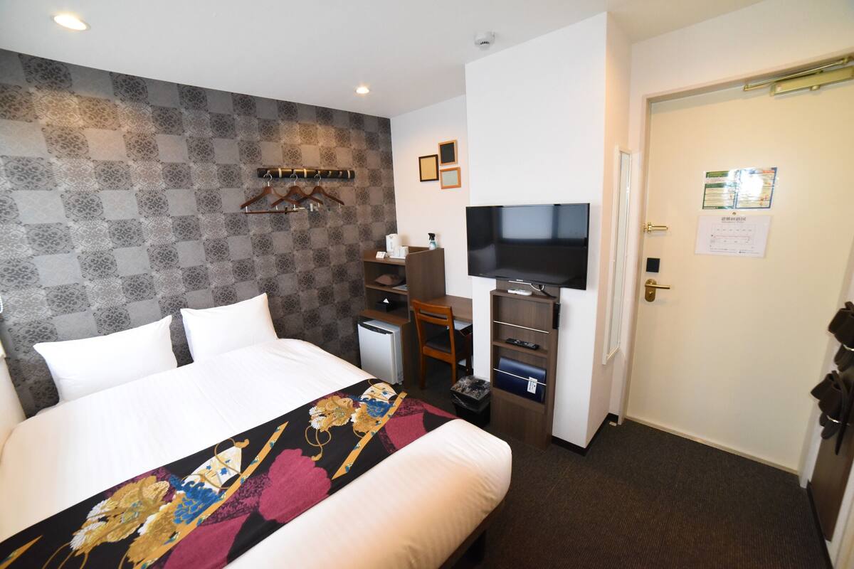 Una habitación de hotel con una cama, un escritorio, un televisor y una puerta con un letrero.