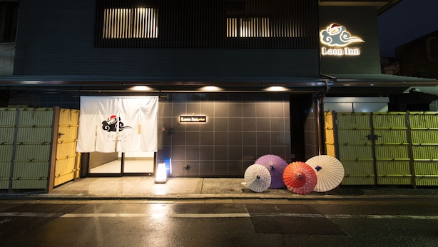 A building with a neon sign reading "Laon Inn" and a closed entrance. There are three umbrellas on the sidewalk in front of the building. - Laon Inn Gion Nawate (Kyoto)