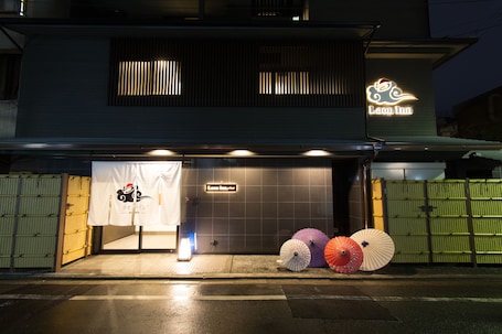 A building with a neon sign reading "Laon Inn" and a closed entrance. There are three umbrellas on the sidewalk in front of the building.