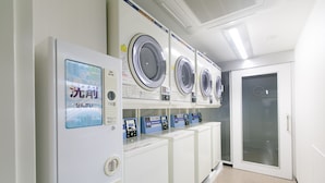 A laundry facility with multiple washing machines and dryers, a control panel, and a glass door. - Laon Inn Gion Nawate (Kyoto)