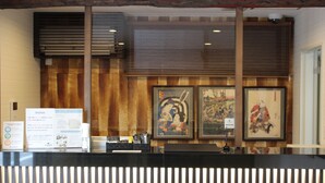 A reception desk with framed artwork on the wall, a bulletin board with notices, and a wooden panel design. - Laon Inn Gion Nawate (Kyoto)