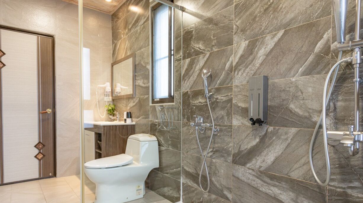 A modern bathroom with a toilet, a shower, and a vanity with a mirror.
