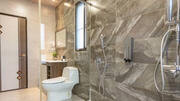 A modern bathroom with a toilet, a shower, and a vanity with a mirror.