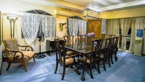 Un comedor con una mesa de vidrio rodeada de sillas ornamentadas, un sillón de estilo vintage y una lámpara de pie decorativa.