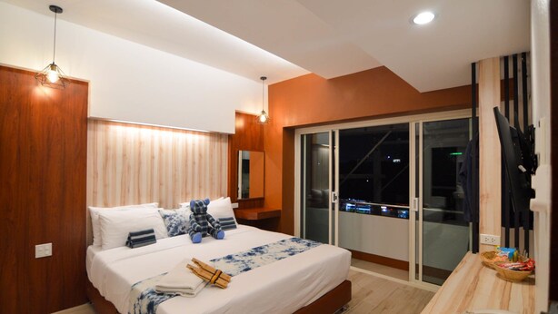 Una habitación de hotel moderna con una cama grande, paneles de madera, un balcón con vistas a la ciudad y un escritorio con teléfono.