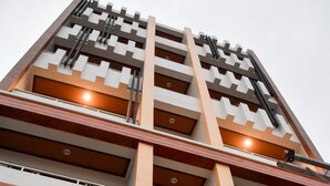 Un edificio de varios pisos con un diseño arquitectónico moderno, que presenta una serie de balcones y grandes ventanales.