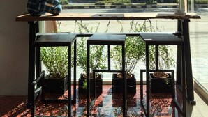 Una habitación con un ventanal grande, un banco de madera y plantas en macetas.