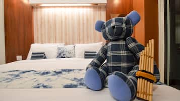 Una cama con un peluche de oso escocés y un cepillo de bambú.
