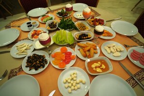 A table set with various dishes including salads, fruits, and appetizers. - Malabadi Hotel (Diyarbakir)